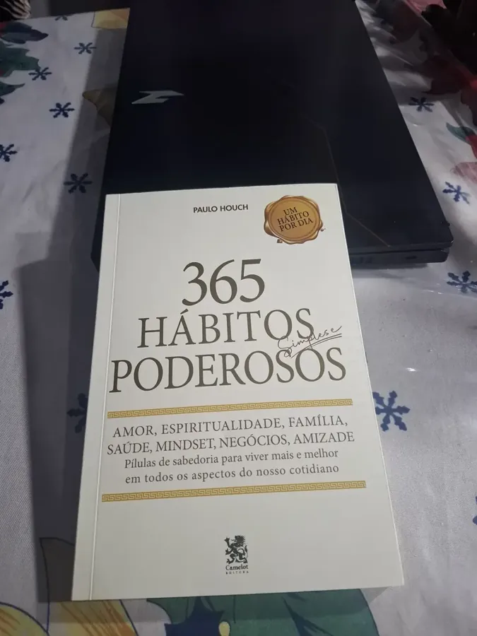 Livro apoiado sobre a mesa ao lado do notebook